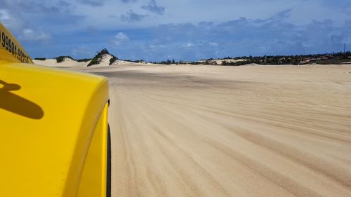 Yellow road by desert against sky