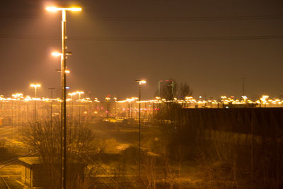 Illuminated city street against sky at night