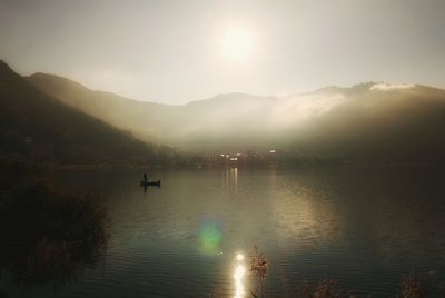 Scenic view of lake by silhouette mountain against sky