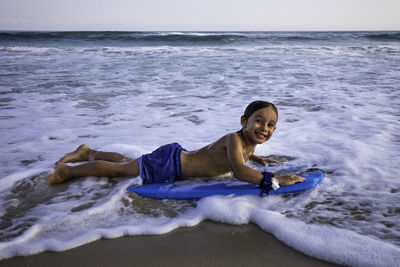 Happy 5 years old kid on a boogie board at the beach