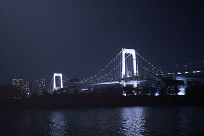 Illuminated bridge over river at night