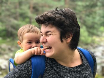 Mother biting baby finger while carrying him at forest