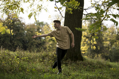 Young man dancing against tree