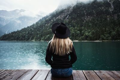 Rear view of woman looking at lake against mountain