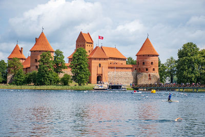 Buildings by river against sky