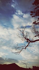 Low angle view of bare tree against cloudy sky
