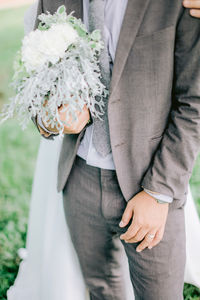 Midsection of couple holding bouquet