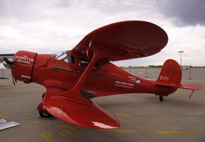 Red airplane on airport runway against sky