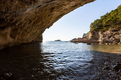 Rocky cliff in the sea and a small yacht in the background