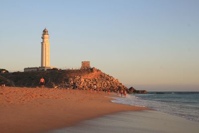 Lighthouse on beach against clear sky