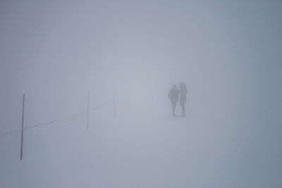 Rear view of people on snow covered field