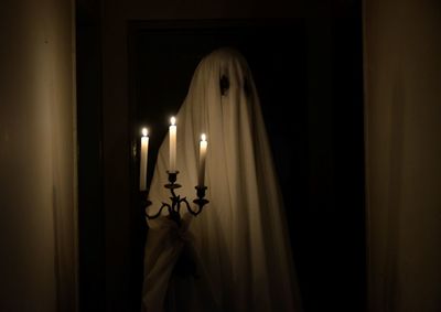Ghost holding candles in darkroom
