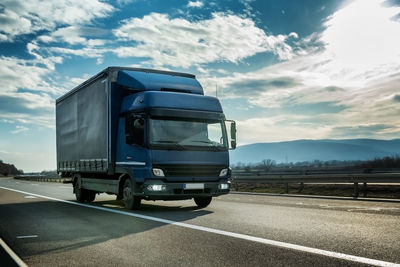 Truck on road against cloudy sky