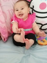 Portrait of cute baby girl lying on bed