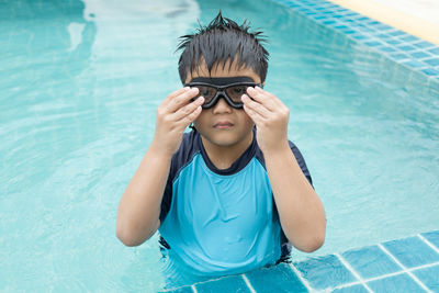 Close-up shot of a boy putting on swim goggles.boys preparing for swimming lessons in the pool