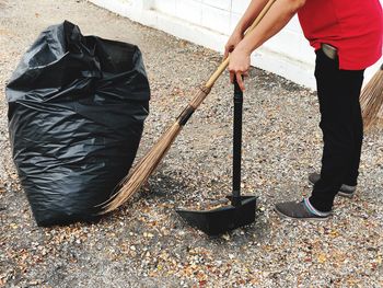 Low section of man cleaning leaves on footpath