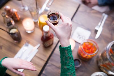 High angle view of woman holding wine glasses on table