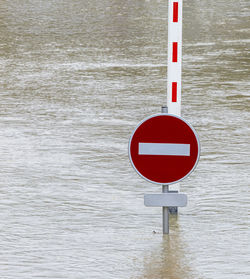 Close-up of arrow sign hanging by lake