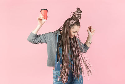 Low angle view of woman standing against pink background