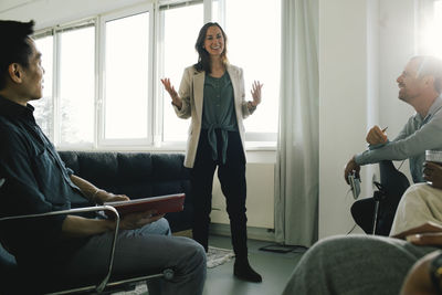 Businesswoman talking to colleagues while standing during meeting at office