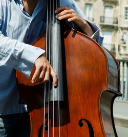 Midsection of man playing double bass