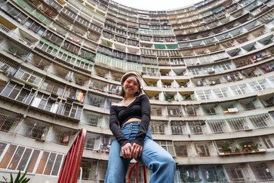 Full length portrait of young man sitting in city