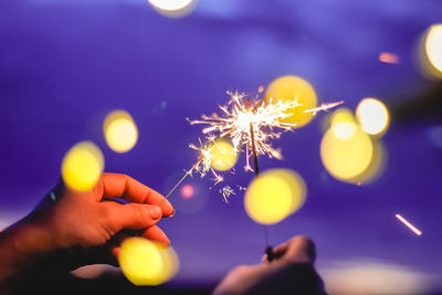 Blurred motion of person hands holding sparkler at night