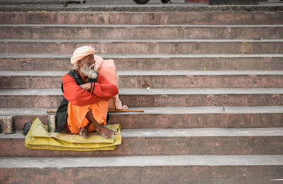 Homeless senior man sitting on steps 