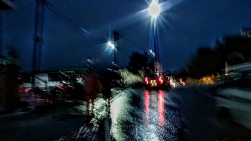 Blurred motion of illuminated trees against sky at night