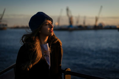 Side view of young woman looking away at the sunset in the port of hamburg