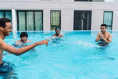 Young people making jokes inside a pool surrounded