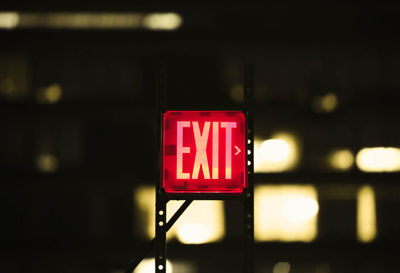 Close-up of illuminated exit sign at night