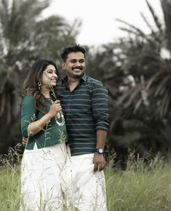 Portrait of smiling couple standing against trees