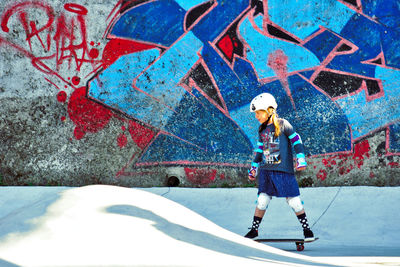 Girl skating against old graffiti wall