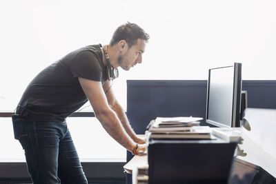 Side view of businessman using computer at desk in office