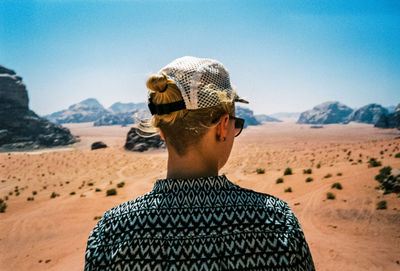 Low section of person on mountain against sky on sunny day