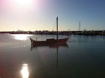 Sailboats moored on sea against clear sky during sunset