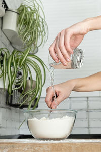 Pouring water into flour. making dough by female hands in white modern kitchen. flour and water