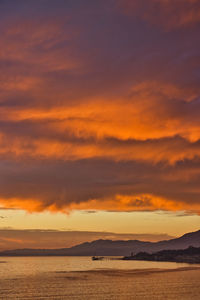 Scenic view of sea against dramatic sky during sunset