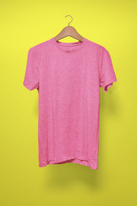 Pink umbrella hanging on yellow wall