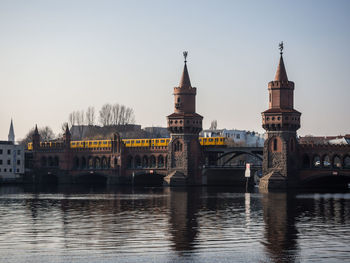 Bridge over river in city against clear sky