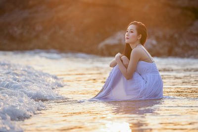 Young woman sitting on land in water