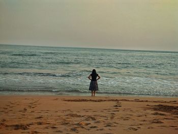 Rear view of woman on beach against sky