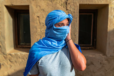 Portrait of man wearing woman standing against built structure