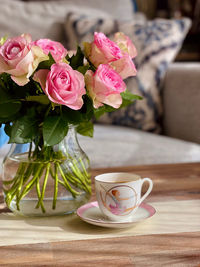 Close-up of flower vase on table with cup of coffee and roses