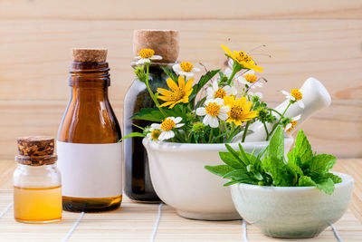 Close-up of flowers in mortar and pestle by bottle on table