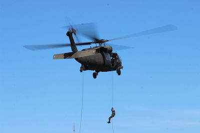 Low angle view of helicopter flying against clear blue sky