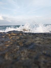 Scenic view of sea waves splashing on shore against sky