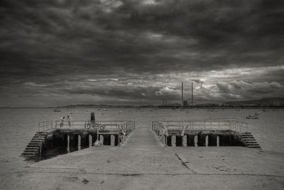 Pier on sea against cloudy sky