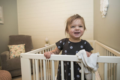 Portrait of cute toddler girl in her crib in bedroom.
